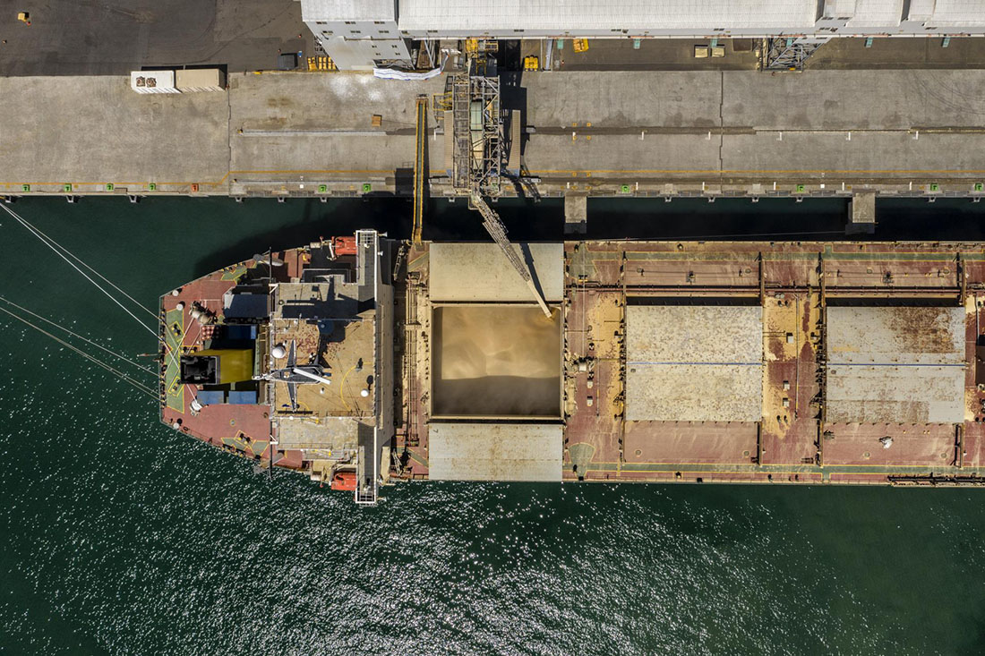 Overhead view of cargo ship being loaded with grain.