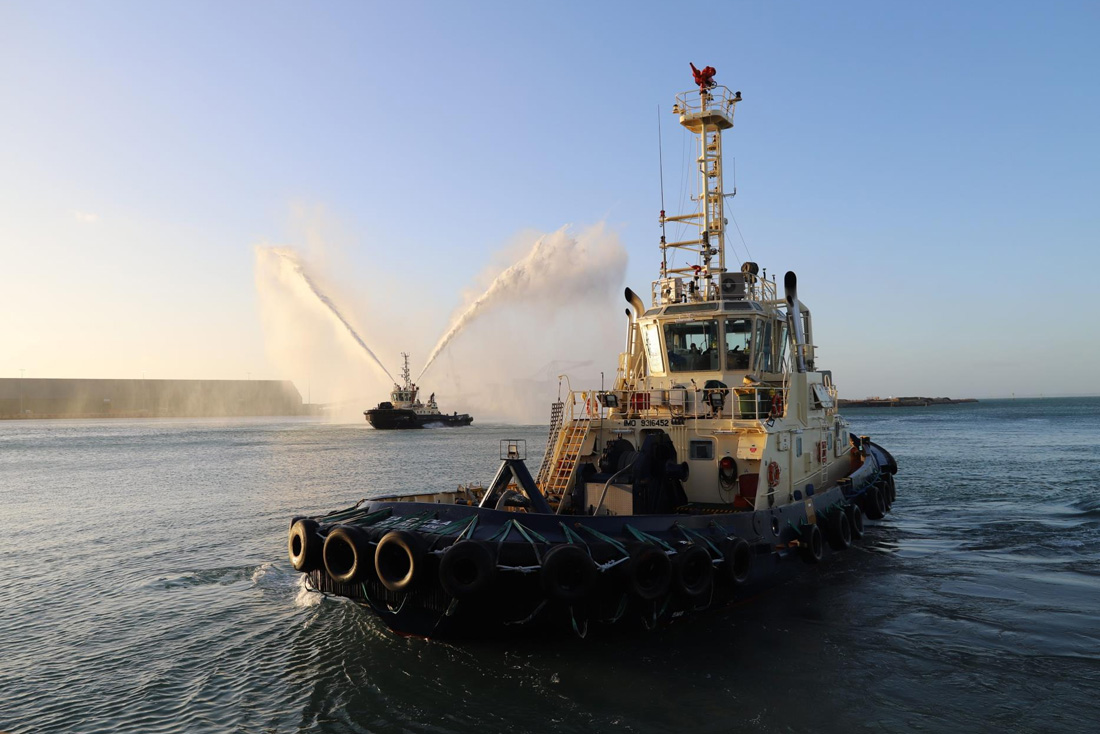 Close up of tugboat with second tugboat behind it spraying water up and out the top sides