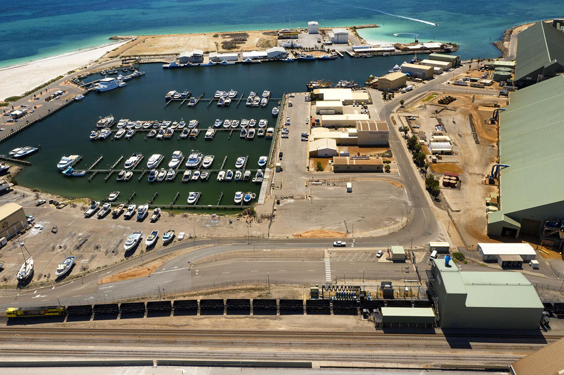 Overhead view of Fishing Boat Harbour on left with road and sheds on the right.