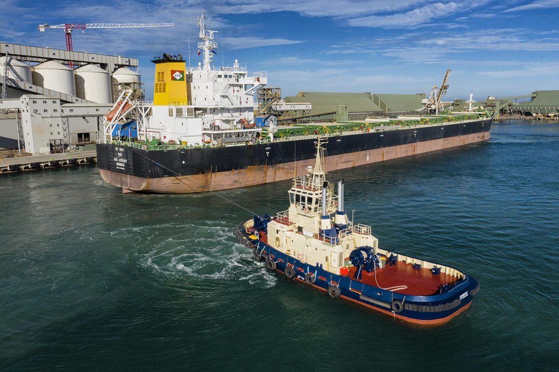 Tugboat perpendicular to cargo ship in port